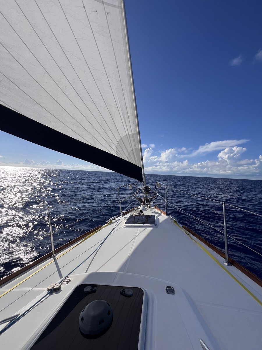 Under sail on open ocean, bow of sailboat cutting through deep blue water