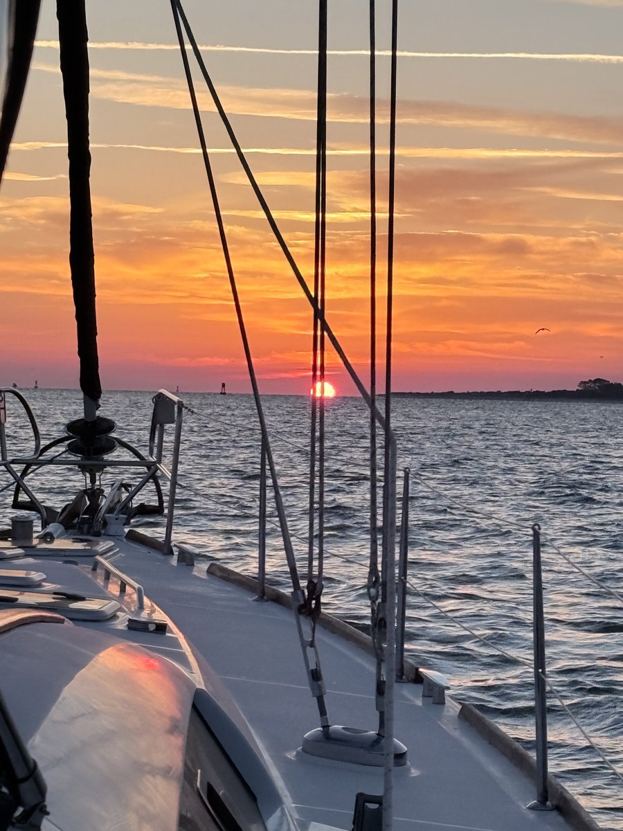 Sunset over open water from the deck of a sailboat